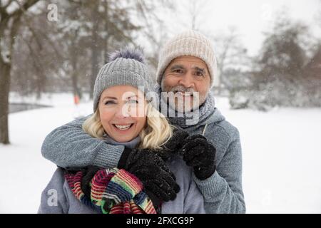 Homme âgé avec le bras autour de la femme au parc pendant l'hiver Banque D'Images
