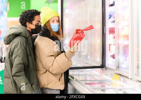 Des amies multi-ethniques magasinent dans un supermarché pendant la COVID-19 Banque D'Images