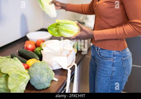 Femme de taille moyenne qui vérifie les articles d'épicerie sur le comptoir de la cuisine à la maison Banque D'Images