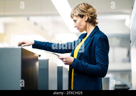 Femme professionnelle avec tablette numérique en usine d'impression Banque D'Images