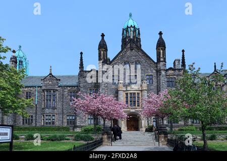 Toronto, Canada - le 9 mai 2021 : l'extérieur de style gothique de l'un des plus anciens édifices universitaires de l'Université de Toronto, avec des arbres qui fleurissent dans les Banque D'Images