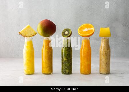 Smoothies aux fruits en pots, quartiers d'ananas et de kiwis, banane et mangue et orange Banque D'Images