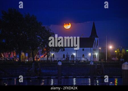 Swansea, Royaume-Uni. 26 mai 2021. La super lune de sang de fleur disparaît dans les nuages au-dessus du Centre norvégien des arts de l'église à Cardiff Bay, au sud du pays de Galles ce soir. Credit: Phil Rees/Alamy Live News Banque D'Images