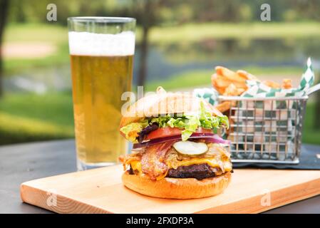 Un cheeseburger au bacon avec des frites et un verre de bière. Banque D'Images