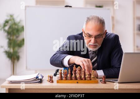 Un vieux employé d'homme d'affaires jouant aux échecs sur le lieu de travail Banque D'Images
