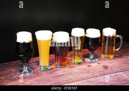 Six verres de différents types de bière sont sur une table en bois à la suite. Gros plan. Banque D'Images