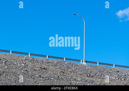 Un lampadaire par une rambarde sur une route inclinée vers le haut Banque D'Images
