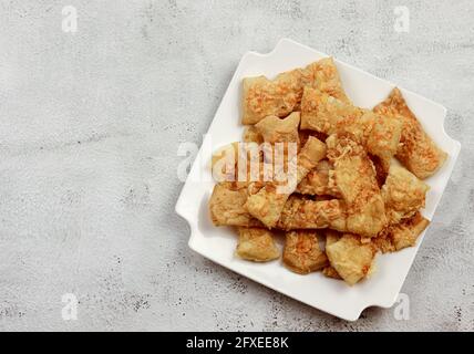 Pailles de pâte feuilletée au fromage sur une plaque rectangulaire blanche sur fond gris clair. Vue de dessus, plan d'appartement Banque D'Images