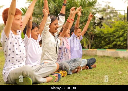 Vue latérale, groupe de jeunes enfants qui applaudissent au parc - adolescents qui s'amusent pendant les vacances d'été au camp - enfants multiethniques qui jouent joyeusement Banque D'Images