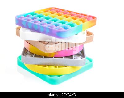 Jouets antistress sensoriels colorés à bulles pop-push, empilés dans un tas isolé sur fond blanc Banque D'Images
