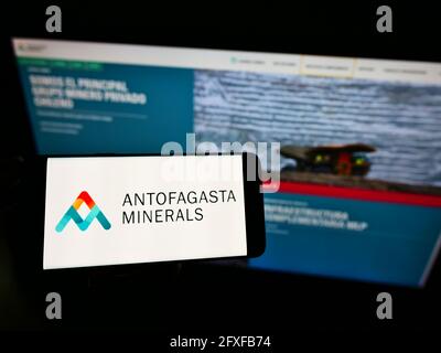 Personne tenant un smartphone avec le logo de la société minière Antofagasta Minerals S.A. à l'écran devant le site Web d'affaires. Mise au point sur l'affichage du téléphone. Banque D'Images