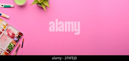 Vue de dessus de l'espace de travail de conception avec outils de peinture, décorations et espace de copie sur fond rose Banque D'Images