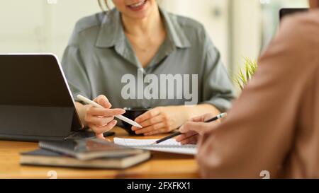Plan court de deux employées de bureau consultant d'autres travaux assis en face l'un de l'autre dans la salle de bureau Banque D'Images