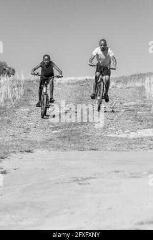 HARRISMITH, AFRIQUE DU SUD - 05 janv. 2021: Harrismith, Afrique du Sud - octobre 18 2012: Enfants africains à vélo dans un village rural Banque D'Images