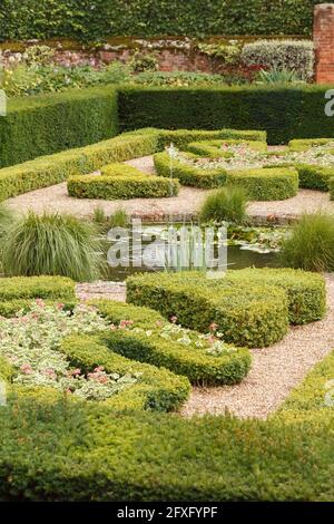 Haie tronquée (buxus) dans un jardin anglais géométrique formel avec étang et fontaine, Royaume-Uni Banque D'Images