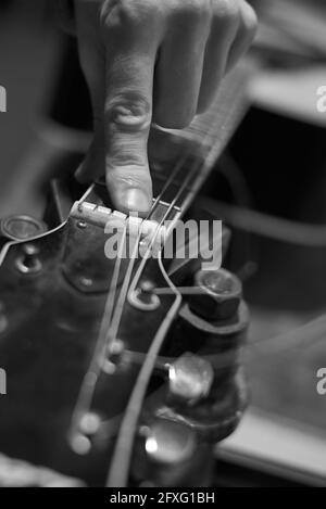 Un employé de service vérifie le son de la guitare pour un réglage plus poussé, la photo tonifiée. Banque D'Images