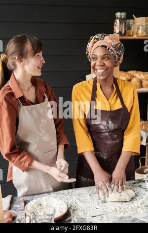Deux jeunes femmes rient et parlent tout en cuisinant ensemble la cuisine Banque D'Images
