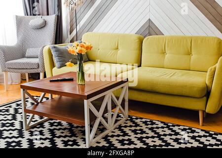 séjour avec canapé vert clair et table basse en bois avec fleurs Banque D'Images