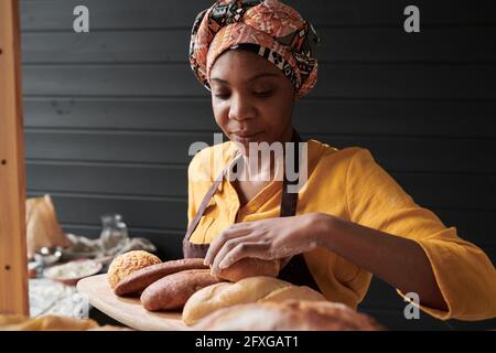 Une jeune femme africaine prend le pain frais dans lequel elle travaille la boulangerie Banque D'Images