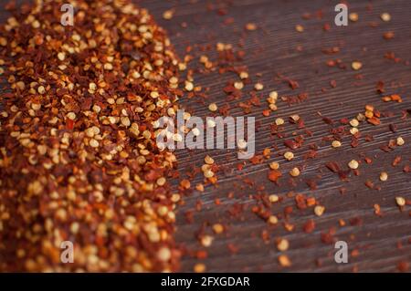 Flocons de piment rouge sur une table en bois. Concept de cuisson, assaisonnements pour les aliments. Banque D'Images