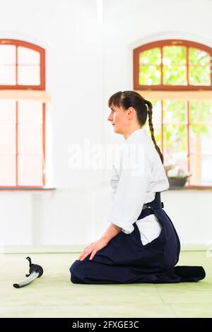 Femme assise sur des nattes en aïkido en école d'arts martiaux Banque D'Images