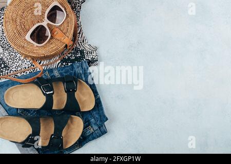 Flat lay avec vêtements et accessoires été pour femme. T-shirt à imprimé animal, sandales, short en denim bleu, sac en rotin biologique tendance, lunettes de soleil. V Banque D'Images