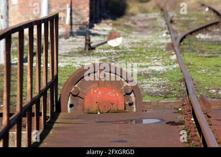 Grande couronne de chemin de fer ancienne rouillée d'époque ou roue dentée de passage de roue montée sur le côté des voies ferrées utilisées pour tourner le matériel roulant ou les locomotives Banque D'Images
