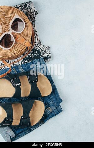 Flat lay avec vêtements et accessoires été pour femme. T-shirt à imprimé animal, short en denim bleu, sac en rotin biologique tendance, lunettes de soleil. Vacances, Banque D'Images