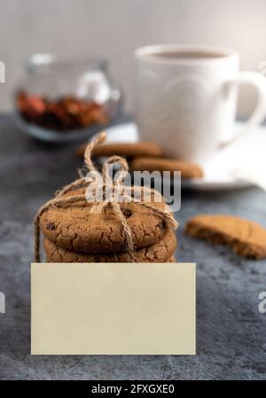 Table avec une tasse de café ou de thé et biscuits éclairés par la lumière du matin, autocollant vierge pour inscription Banque D'Images