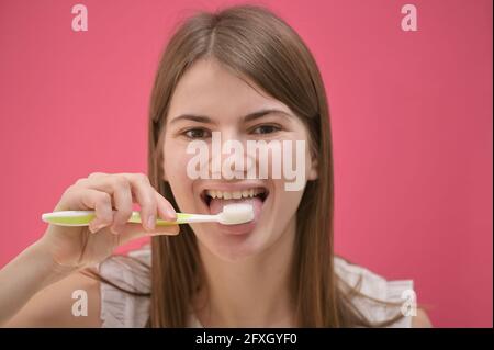 Jeune femme nettoyage de la langue à l'aide d'une brosse à dents en studio Banque D'Images