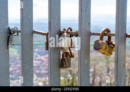 Vieux cadenas fermés rouillés sur une clôture en métal. Un symbole d'amour et de romance pour toujours. L'idée de la Saint-Valentin. Sur un fond de ciel et de nature en flou Banque D'Images