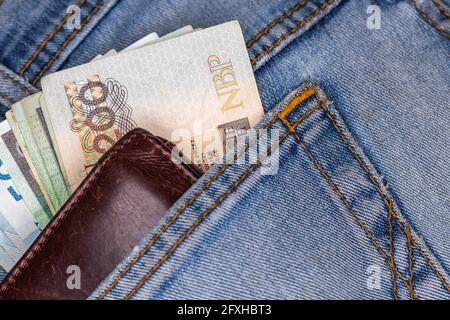 Portefeuille et beaucoup de billets polonais sortant de la poche arrière du pantalon en denim. Photo prise sous une lumière artificielle douce Banque D'Images