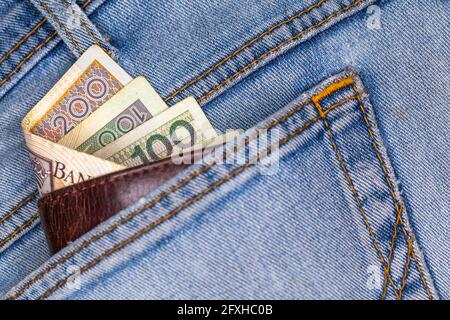 Portefeuille et beaucoup de billets polonais sortant de la poche arrière du pantalon en denim. Photo prise sous une lumière artificielle douce Banque D'Images