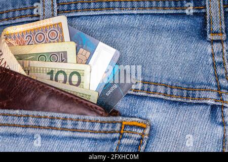 Portefeuille et beaucoup de billets polonais sortant de la poche arrière du pantalon en denim. Photo prise sous une lumière artificielle douce Banque D'Images