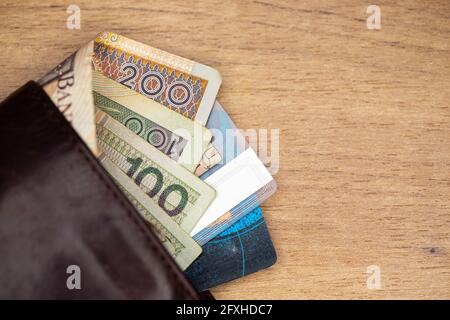 Beaucoup de billets polonais et de cartes de crédit sortent d'un portefeuille en cuir marron. Photo prise sous une lumière artificielle douce Banque D'Images