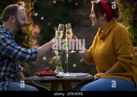 Couple heureux en dégustant du champagne et des raisins de Corinthe rouges à la table du patio Banque D'Images