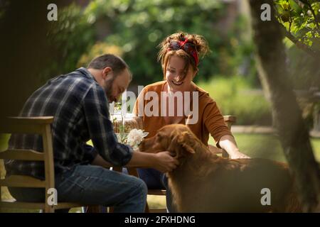 Couple heureux avec chien Golden Retriever à la table du jardin Banque D'Images