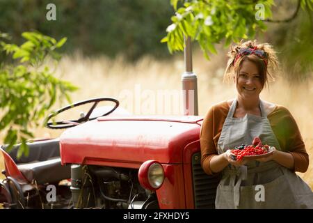 Portrait bonne fière femme au tracteur avec des raisins de Corinthe rouges frais Banque D'Images