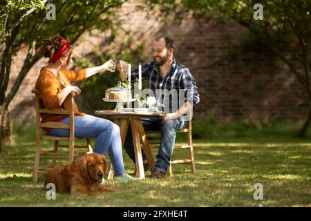 Couple heureux avec des lunettes de toaster pour chiens à table dans le jardin d'été Banque D'Images