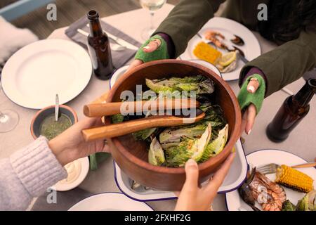 Des amis passent une salade sur une table de jardin Banque D'Images