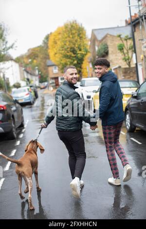 Portrait heureux gay homme couple chien marchant sur la route humide d'automne Banque D'Images