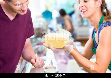 Vendeuse au supermarché bio fromage client offre compteur Banque D'Images