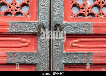 Ferrures richement décorées avec des serpents sur le vieux bois rouge porte Banque D'Images