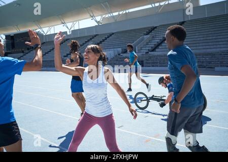 Des jeunes athlètes heureux, des amis qui se sont élevés sur une piste de sport bleue ensoleillée Banque D'Images