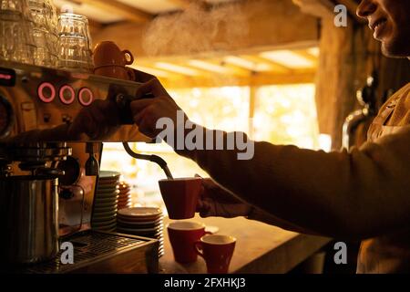 Un barista masculin prépare du cappuccino à la machine à espresso du café Banque D'Images