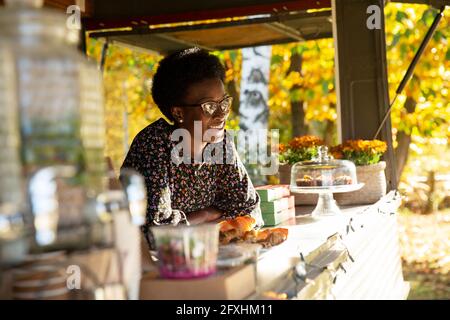 Bonne femme propriétaire de chariot alimentaire dans un parc ensoleillé Banque D'Images