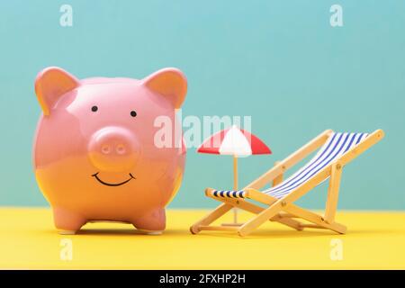 Banque de porc rose, chaise de jeu et parasol sur fond coloré, concept d'économie d'argent de vacances. Banque D'Images