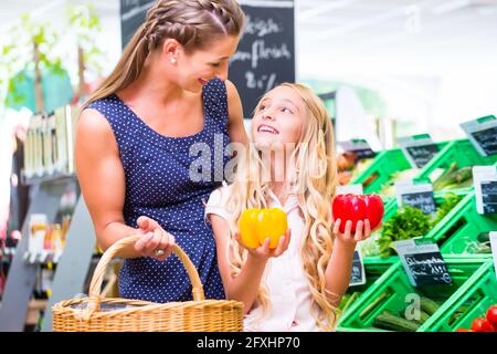 La mère et la fille choisissent des légumes tout en faisant des courses biologiques supermarché Banque D'Images