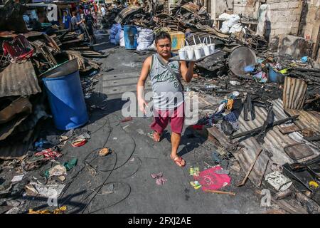 Manille. 27 mai 2021. Un résident porte des tasses de porridge pour ses voisins après un incendie dans un bidonville de Manille, aux Philippines, le 27 mai 2021. Crédit: Rouelle Umali/Xinhua/Alamy Live News Banque D'Images