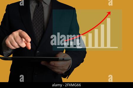 Homme d'affaires tenant une tablette en regardant le volume de ventes croissant ou l'augmentation de la valeur des actions au cours de la dernière période. Demande croissante. Banque D'Images